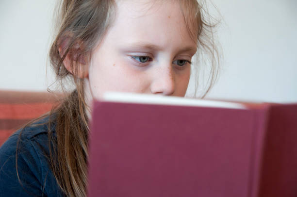 istock A little school girl reading a book. 665602848