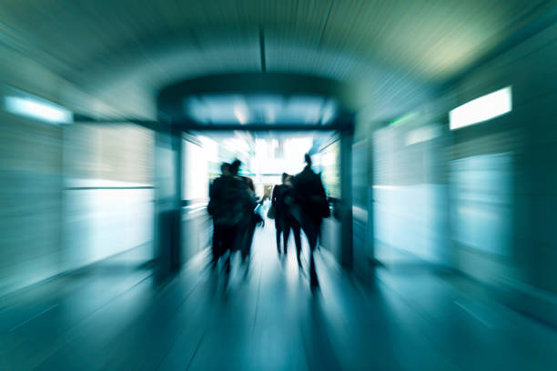 Silhouettes of walking people in a subway corridor, blurred motion, rear view, back lit