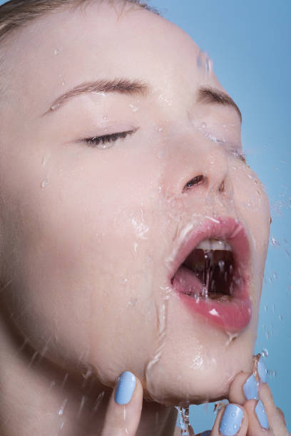 istock Portrait of a blonde close-up on whose face water is pouring. 665608704