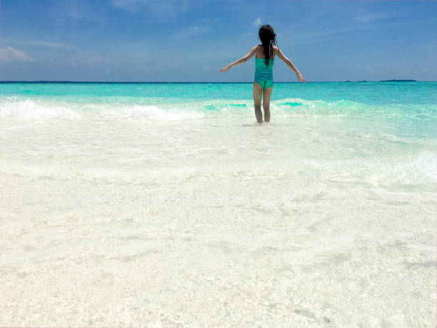 istock Little Girl Play With Waves On Tropical Beach 665613696