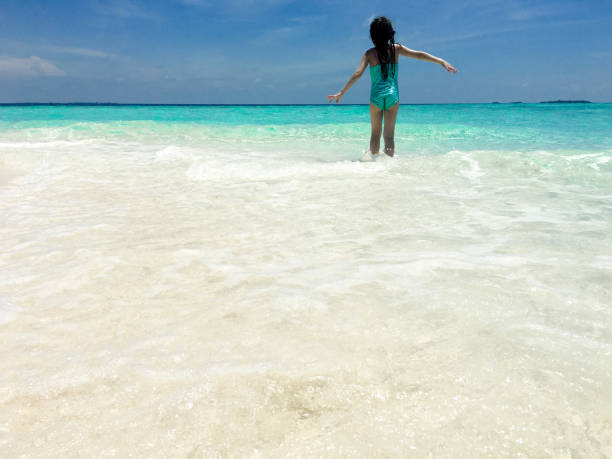 istock Little Girl Play With Waves On Tropical Beach 665613702
