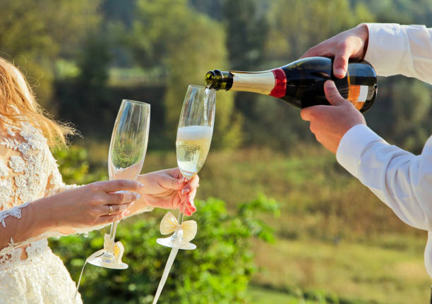 istock Groom pours champagne in wineglasses 665622768