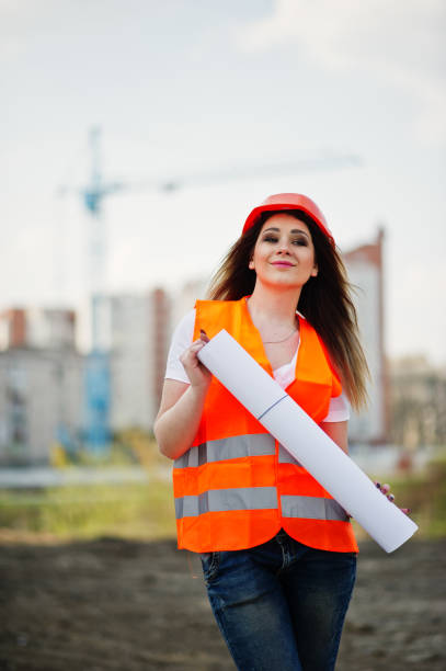 istock Engineer builder woman in uniform waistcoat and orange protective helmet 665630284