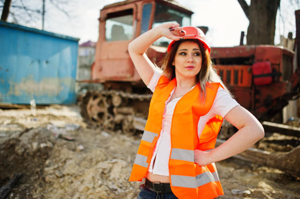 istock Engineer builder woman in uniform waistcoat and orange protective helmet 665630400
