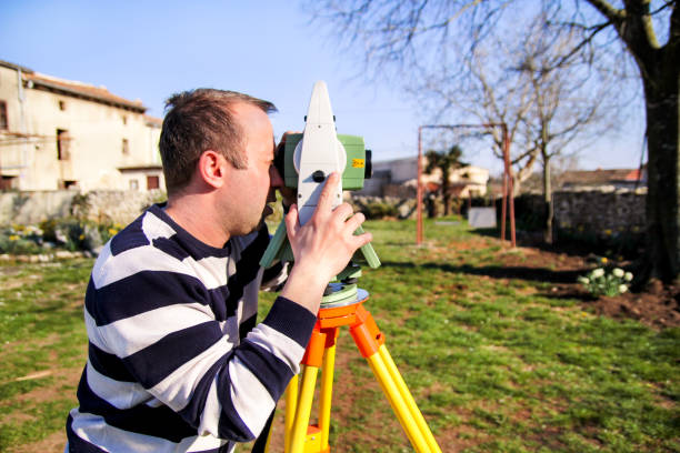 istock Man using of total station. Guy surveyor at work. Survey Instrument geodetic device, total station set in the field. Surveyor worker making measurement in the garden. 665630952