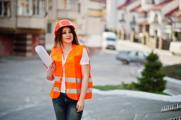 istock Engineer builder woman in uniform waistcoat and orange protective helmet 665631086