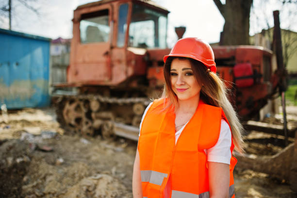 istock Engineer builder woman in uniform waistcoat and orange protective helmet 665631092