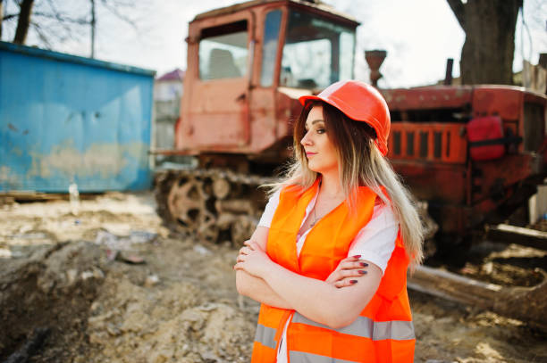 istock Engineer builder woman in uniform waistcoat and orange protective helmet 665631108