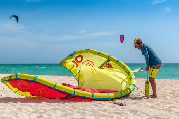 Kiteboard school instructor with air pump inflating a kiteboard at Miami Beach shoreline