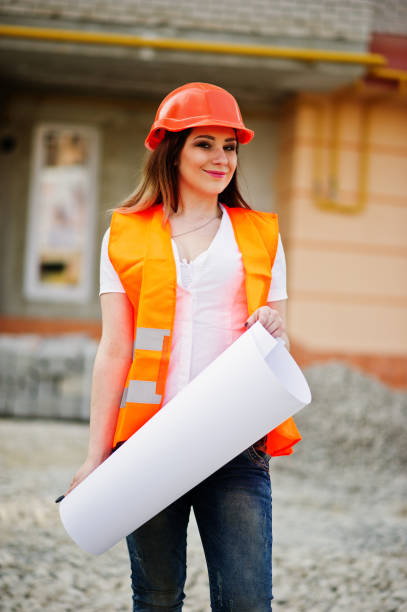istock Engineer builder woman in uniform waistcoat and orange protective helmet 665636848