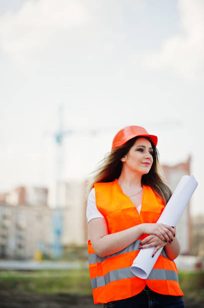 istock Engineer builder woman in uniform waistcoat and orange protective helmet 665636992