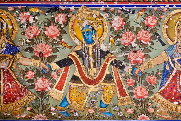 Lord Krishna dancing on a 19th century fresco with golden paint on carved wall of India.
