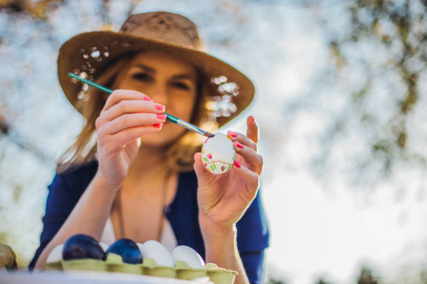Beautiful woman decorating easter eggs in garden for holiday