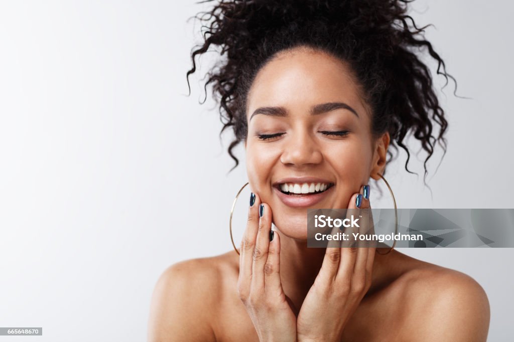 Portrait of happy female with her eyes closed Portrait of happy female with her eyes closed touching a face against gray background Skin Stock Photo