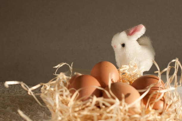 istock Easter rabbit inside a sieve full of easter eggs on rustic wood 665648808
