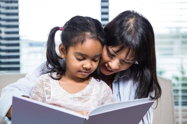 istock Happy mother reading book with her daughter 665667378