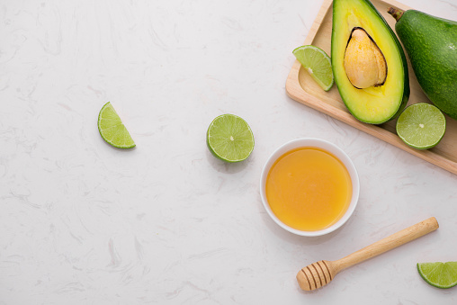 Healthy food concept. Fresh organic avocado and lime with honey on table