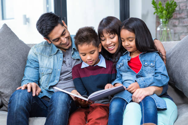istock Happy young family reading a book together 665687300