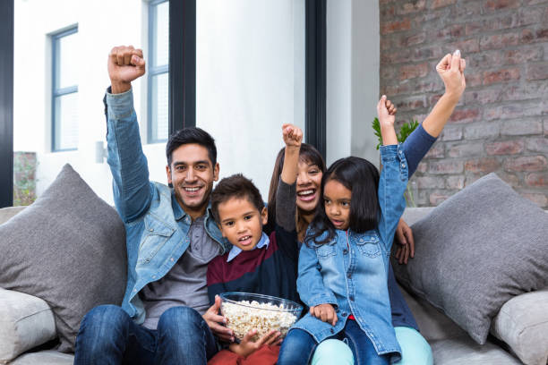 istock Happy young family eating popcorn while watching tv 665688282