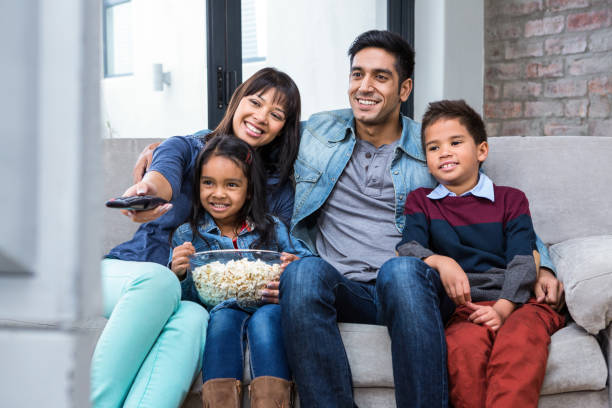 istock Happy young family eating popcorn while watching tv 665689594