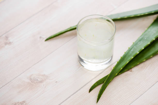 Glass of aloe vera juice with fresh leaves Glass of aloe vera juice with fresh leaves on a wooden table aloe juice stock pictures, royalty-free photos & images