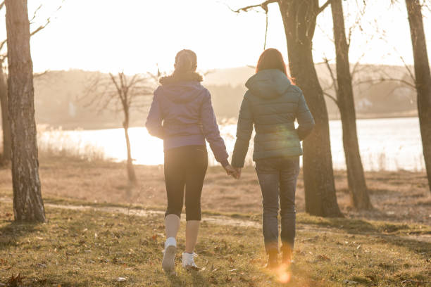 istock sisters walking in park and holding hands 665698706