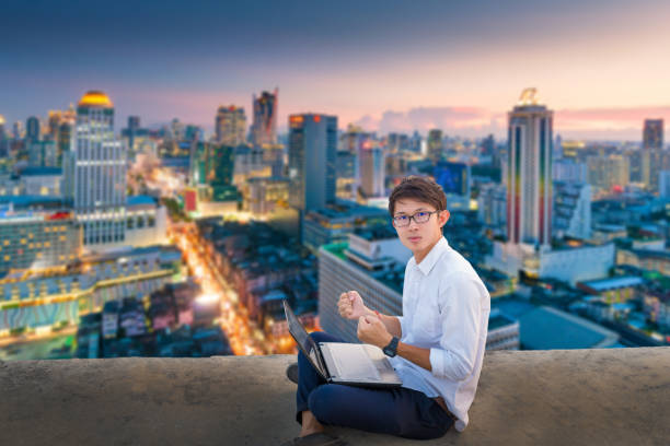 istock Young business man using laptop and digital tablet cityscape background 665708584