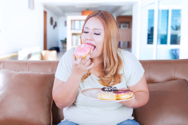 istock Blonde obesity woman eats donuts 665711814