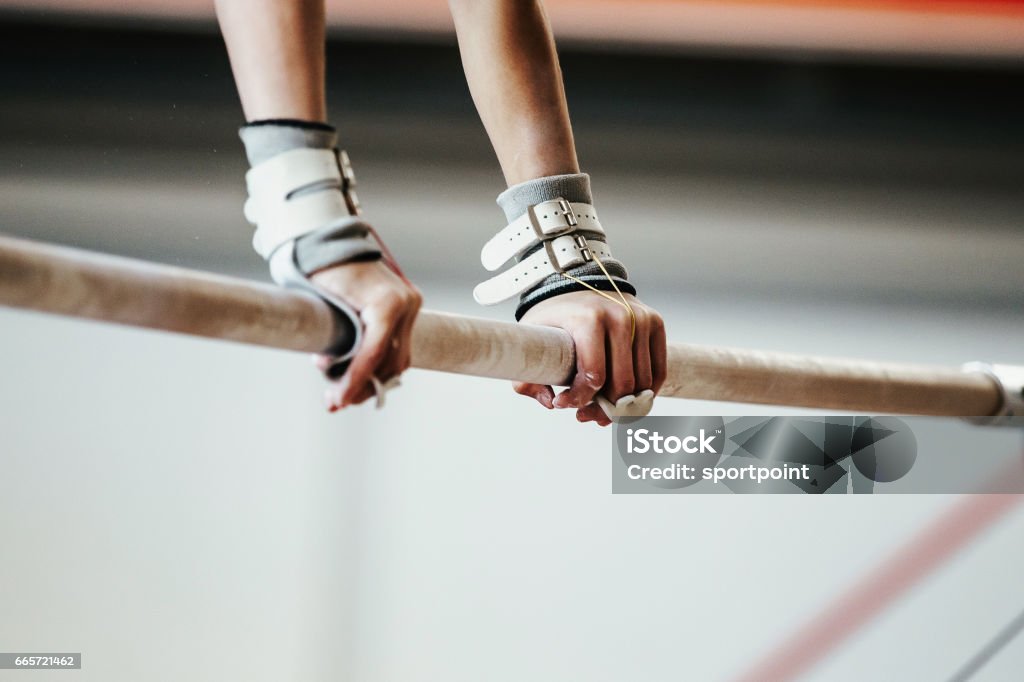 les mains saisissent les athlètes femmes exercices gymnastes sur les barres inégales - Photo de Gymnastique sportive libre de droits