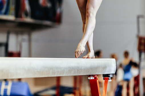 feet woman gymnast exercises on balance beam competition in artistic gymnastics