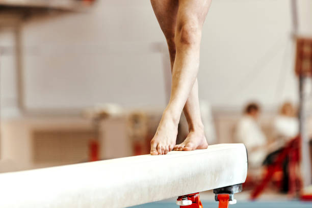 piernas de primer plano mujeres gimnastas ejercicios en el haz de equilibrio - barra de equilibrio fotografías e imágenes de stock