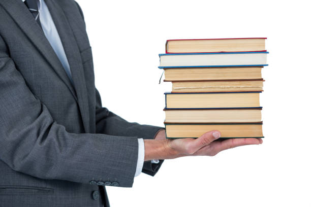 istock Mid section of businessman holding stack of books 665728044