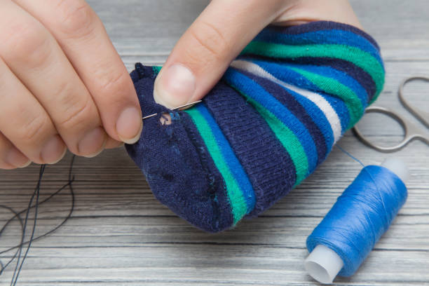 istock Hand with a needle and thread darning a sock. Sewing works. Handmade. Womanly hobby. 665731438