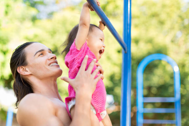 istock Toddler having a great time hanging on the monkey bars with her uncle getting a workout. 665733976