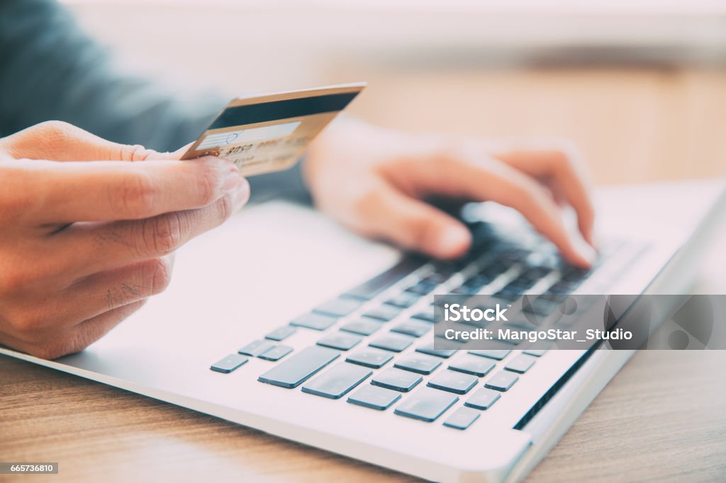 Man making online purchase with credit card Close-up of male hands holding credit or debit card and entering information on laptop. Businessman making online purchase with credit card Credit Card Stock Photo