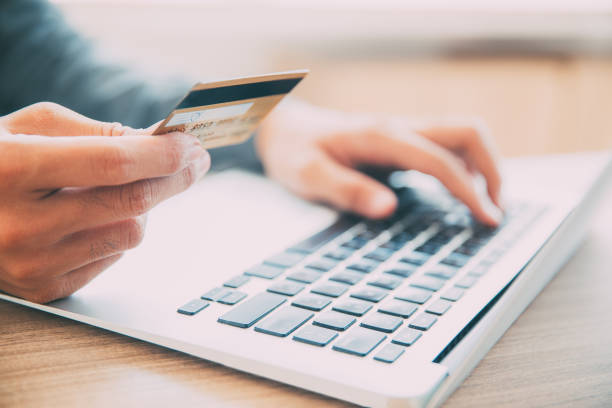 Man making online purchase with credit card Close-up of male hands holding credit or debit card and entering information on laptop. Businessman making online purchase with credit card mobile phone finance business technology stock pictures, royalty-free photos & images
