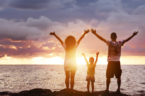 Happy family with son greetings sunset and sea Happy family of father, mother and young son having fun at sunset beach. They greetings sea and sun north shore stock pictures, royalty-free photos & images