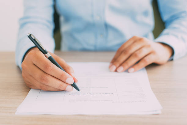 Cropped View of Person Completing Application Form Cropped view of person holding pen and filling out application form on table form submission stock pictures, royalty-free photos & images