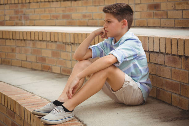 istock Sad schoolboy sitting alone on steps in campus 665757262