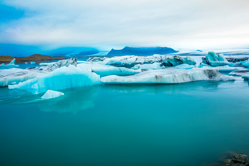 Amazing view of icebergs in glacier lagoon. Scenic view of ice floating on water in Iceland. Stunning view of nature against cloudy sky.