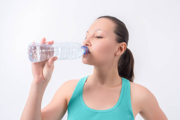 istock Woman drinking water from bottle on a white isolated background 665757778