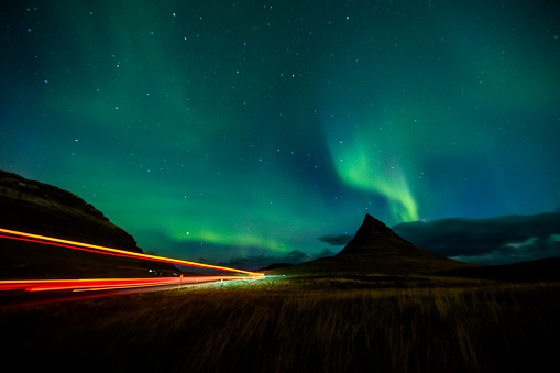 Scenic view of Aurora Borealis over light trails on highway. Idyllic view of Northern Lights in Iceland. Majestic view of nature at night.