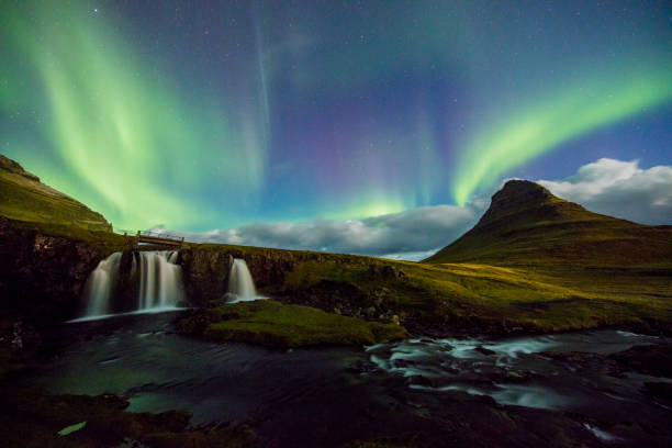istock Amazing view of Aurora Borealis over waterfall 665761160
