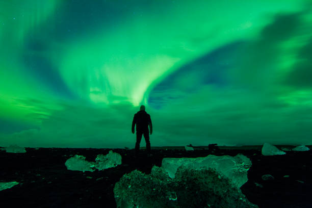 istock Man watching display of Aurora Borealis at beach 665761216