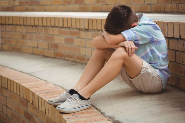 istock Sad schoolboy sitting alone on steps in campus 665761904