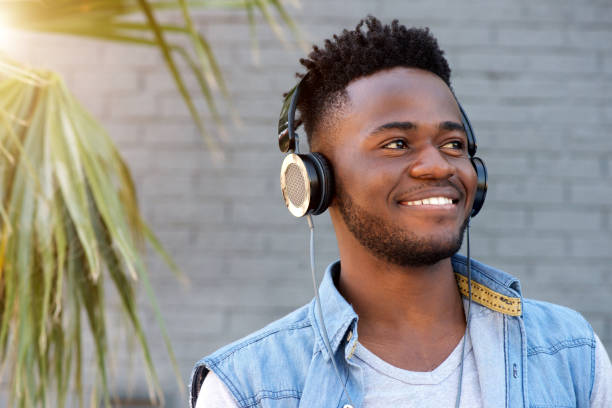 istock young african man smiling with headphones by palm tree 665771478