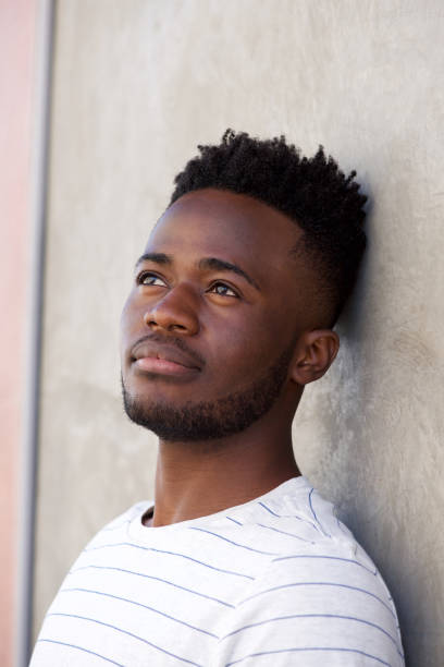 istock pensive adfrican man leaning on wall looking away 665771488