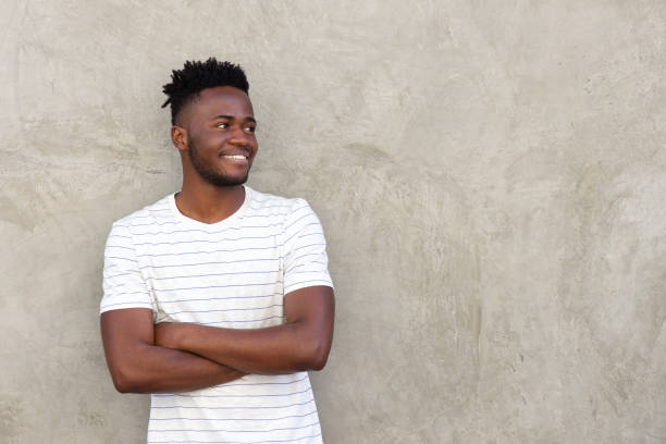 istock handsome man smiling and standing with arms crossed by wall 665771572