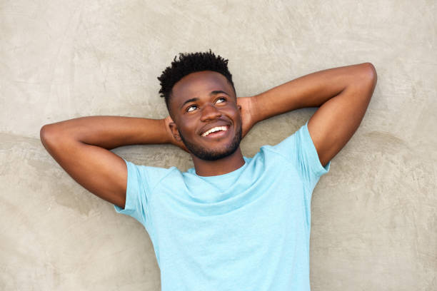 istock carefree man smiling and standing with hands behind head 665771580