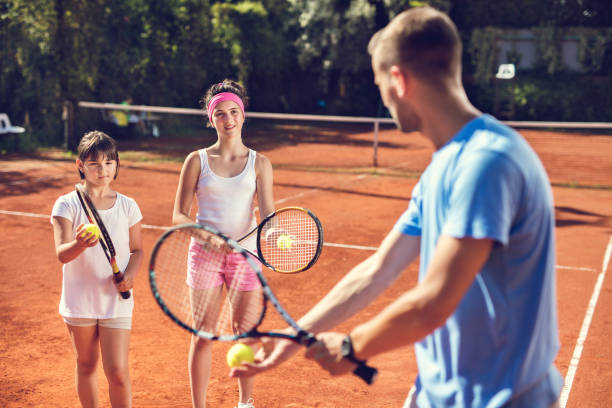 istock Two little girls learning to play tennis with instructor. 665772698